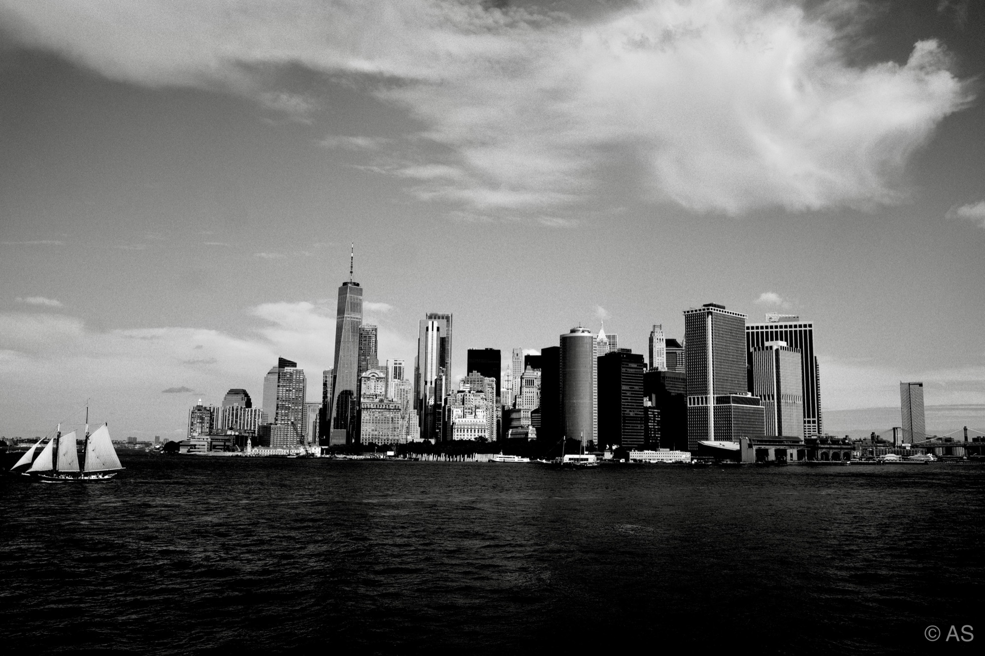 Manhattan skyline across the water with a sailboat in the foreground