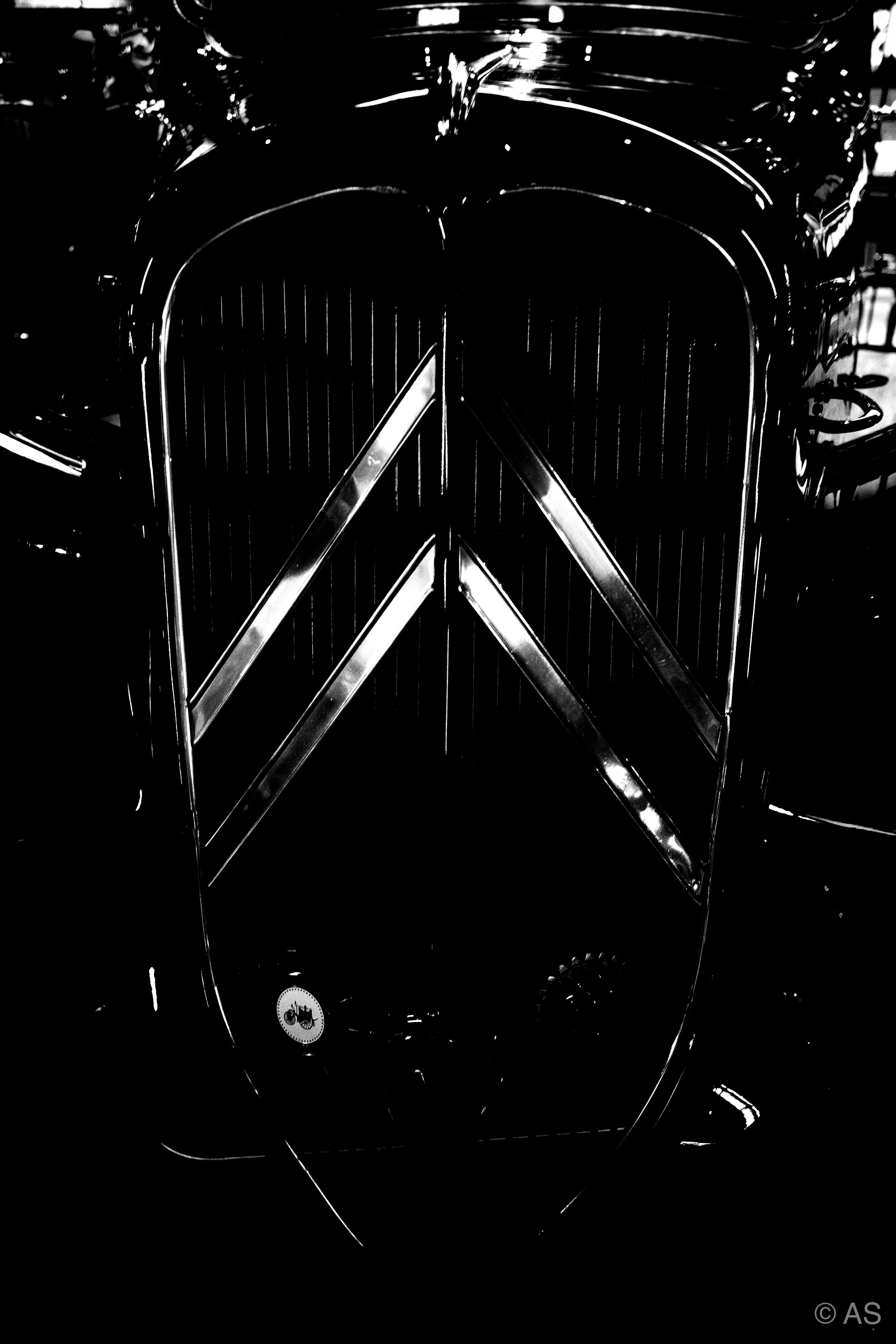 Front grille of a vintage Citroën in near darkness, chrome chevron catching faint light